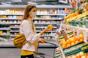 woman holding fruit and shopping basket